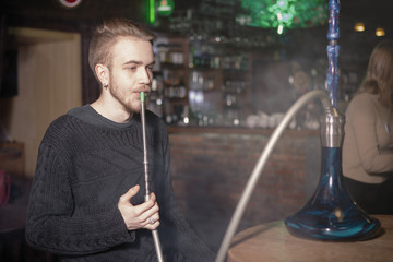 The guy smokes a hookah.