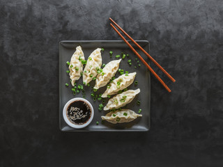 Homemade Meat Dumplings with soy sauce on black square plate in the black background.
