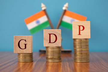 GDP or gross domestic product in wooden block letters on Coins in Increasing order with Indian flag as a background.