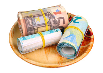 Fototapeta na wymiar Three thousand euros in different bank notes bills are twisted into a rolls and lie on ceramic plate isolated macro