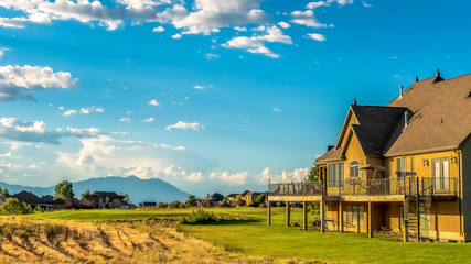 Obraz premium Panorama Scenic landscape with homes on a grassy terrain under blue sky and clouds