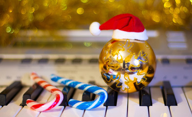Christmas ball, Santa Claus hat and candy on piano keys for Christmas and New Year's Eve_