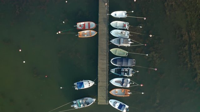 Baots moored to bridge in marina. Top down birds eye aerial view.