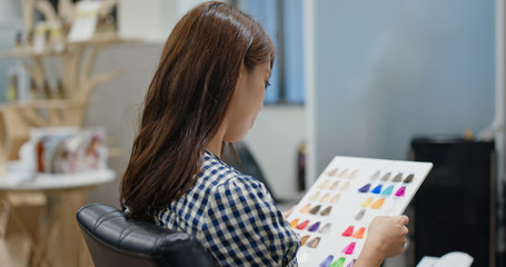 Happy woman at the hair salon, choose the color on book