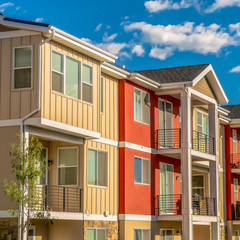 Square frame Colorful home with combination of white and orange wall against cloudy blue sky