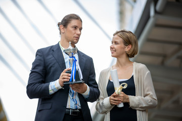 group of joyful business colleagues celebrating their success by winning a trophy and show up trophy while standing in the town