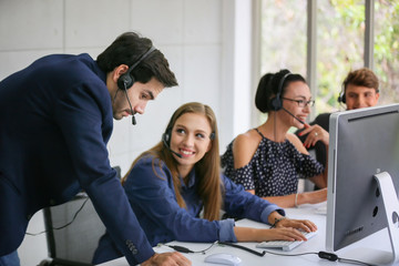Portrait of smiling businesswoman with headset at computer in office 