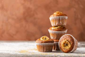 Homemade banana muffins stack on a brown background. Healthy vegan dessert. Close-up selective focus. Horizontal frame.