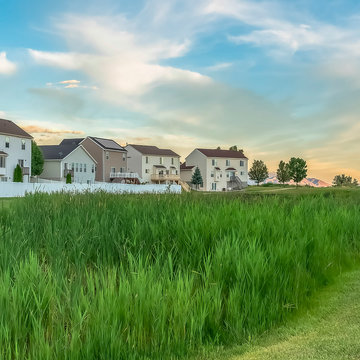 Square Frame Expansive Terrain Covered With Rich Green Grasses In Front Of Family Homes