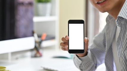 Mockup image of a man holding and showing mobile phone with blank screen and smiley face cropped shot.