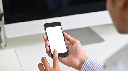 Man's hands touching  mockup smartphone on table office.