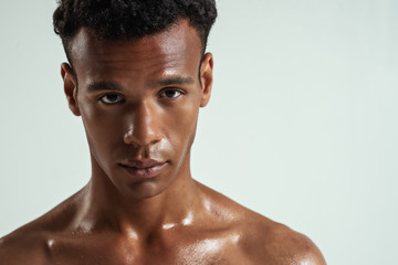 Fototapeta premium Portrait of handsome young african man looking at camera while standing against grey background