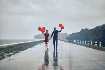 Obraz na płótnie Canvas happy young couple guy and girl are walking in the rain with bubble balls. hello concept autumn, good mood.
