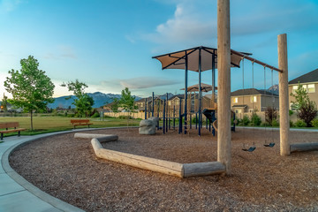 Slides and swings on a park against homes mountain and cloudy blue sky