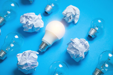Light bulb and crumpled papers in the blue background. Idea