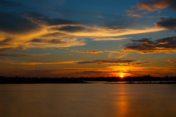 Beautiful Sunset in the sky with sky blue and orange light of the sun through the clouds in the sky, Orange and red dramatic colors over the lake. - Image