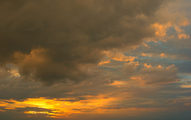 Beautiful Sunset in the sky with sky blue and orange light of the sun through the dark clouds in the sky, Orange and red dramatic colors - Image