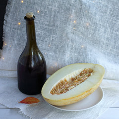 an old misted bottle of wine and a slice of melon with a red leaf on the table. festive autumn still life