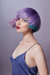 Portrait of a woman with bright colored flying hair, all shades of purple. Hair coloring, beautiful lips and makeup. Hair fluttering in the wind. Sexy girl with short  hair. Professional coloring