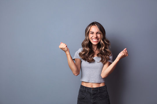 Cheerful Woman Clenching Fists, Exclaiming With Joy And Excitement.