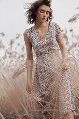 Beautiful girl in a field with tall grass in autumn. Art portrait of a woman, romantic mysterious...