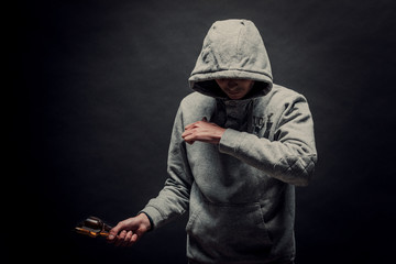 A dangerous hooded man stands in the dark and holds a broken bottle. The face is not visible. The...