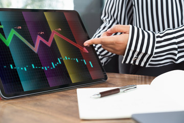 Professional corporate businesswoman pointing at tablet device and explaining financial currency crash graph - Female executive presents declining results at meeting - business and investment concept