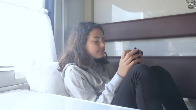 little girl walks on a train compartment car with and a smartphone. travel transportation railroad concept. the girl in the train at the window corresponds the girl in the train wagon at the window