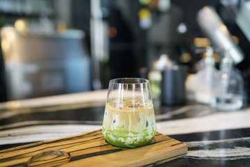 Iced coffee green tea latte  - A glass of iced coffee mixed with milk and matcha on blurred background, , Summer refreshment drink.