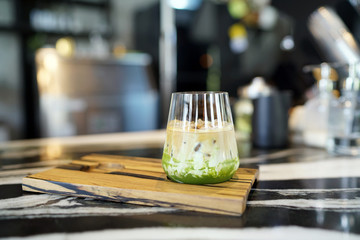 Iced coffee green tea latte  - A glass of iced coffee mixed with milk and matcha on blurred background, , Summer refreshment drink.