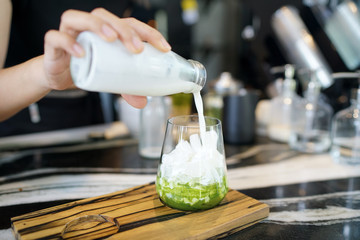 Iced matcha latte - A glass of green tea with milk on the table, Summer refreshment drinks.