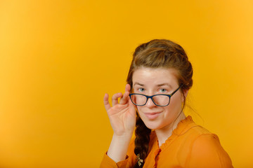 girl with glasses looking at the camera on a yellow background.