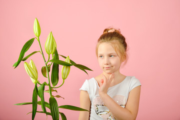 Fashionable and glamorous girl with a flower in the studio on a pink background.