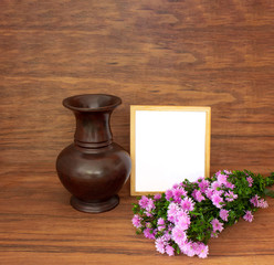 Wooden vase and blank wooden frame with bunch of fviolet lowers on wooden background,brown wood texture,decorative elements