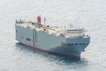 Large gray roll-on/roll-off (RORO or ro-ro) ships or oceangoing vehicle carrier ship anchor in the open sea. Roro ship designed to carry wheeled cargo such as cars, trucks, trailers, etc.
