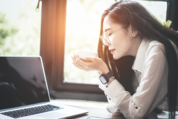 Young woman sitting at cafe table drinking coffee and working on laptop.