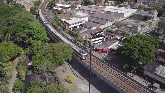 Aerial tilting 4k shot of metro train and station in Medellin city centre