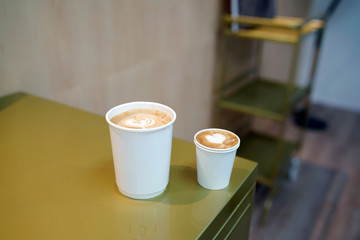 Hot piccolo latte and Flat white - A takeaway cup of coffee with milk and beautiful heart pattern latte art on table and copy space, Perfect for breakfast time.