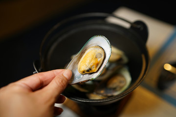 Casserole hot pot of steamed organic mussels with whisky sauce, garlic and herbs served with seafood sauce, New Zealand mussel (Perna canaliculus).