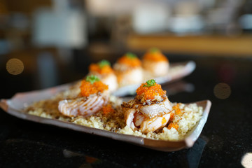 Salmon sushi roll topped with sweet sauce and ebiko roe (Capelin fish caviar) served with crunchy tempura flakes, Traditional Japanese Food.