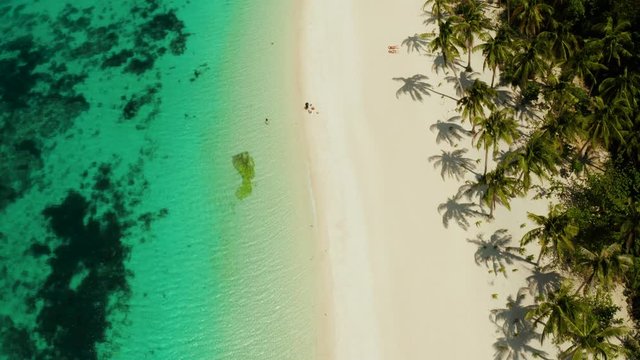 Tropical white sand beach, near the blue lagoon and corall reef from above, Boracay, Philippines. Sandy beach with tourists. Summer and travel vacation concept.