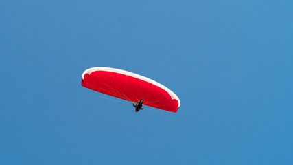Paraglider is flying in the blue sky.