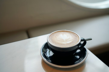Hot Latte - A cup of coffee with milk and beautiful leaf pattern latte art on marble table and blurred background, Perfect for breakfast time.
