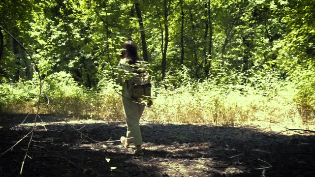 One traveller woman with backpack, white shirt and beiege pants, walking in the sweetgum forest at Mugla Turkey. Turkish tree name is Gunluk.