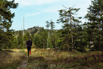 Young man runner run on hill Tristolicnik in Sumava National Park and Bavarian Forest, Czech republic and Germany