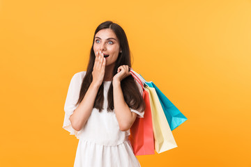 Portrait of excited shopaholic woman wearing dress looking at copyspace while holding colorful shopping bags