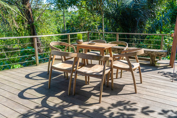 Wooden table and chairs in empty tropical cafe next to rice terraces in island Bali, Indonesia