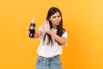 Image of caucasian brunette woman wearing basic clothes rejecting while holding bottle of soda...