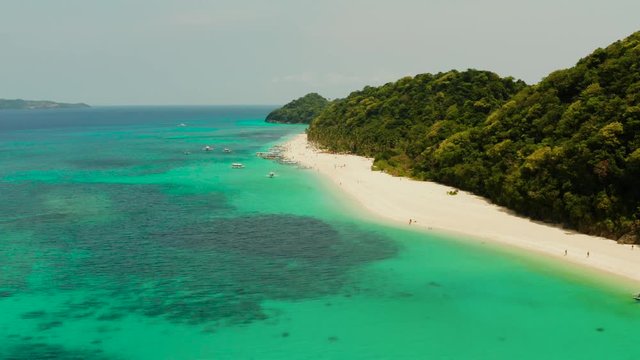 Tropical white sand beach, near the blue lagoon and corall reef from above, Boracay, Philippines. Sandy beach with tourists. Summer and travel vacation concept.