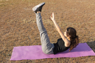 A young slim athletic girl in sportswear with snakeskin prints performs a set of exercises. Fitness...